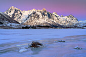 Gefrorener See, im Hintergrund Berge mit schönem Winterhimmel auf den Lofoten, Norwegen. 