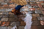 Woman walking through puddles on cobblestones in the rain, Tallinn, Harju County, Estonia, Europe