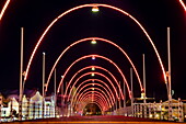 Illuminated Queen Emma Pontoon Bridge connecting Otrabanda and Punda with Dutch influenced architecture of buildings along Handelskade Street in Punda at night behind, Willemstad, Curaçao, Netherlands Antilles, Caribbean
