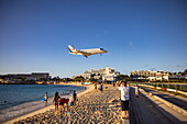 People on Maho Beach admire the landing of a private jet at Princess Juliana International Airport, Saint Martin (Sint Maarten), Caribbean