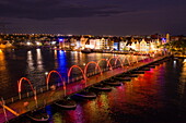 Luftaufnahme der beleuchteten Queen Emma Pontoon Bridge, die Otrabanda und Punda verbindet, mit der niederländisch beeinflussten Architektur von Gebäuden entlang der Handelskade Street in Punda bei Nacht, Willemstad, Curaçao, Niederländische Antillen, Karibik