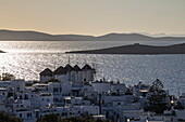 View over town with the famous Mykonos windmills and islands in the distance at sunset, Mykonos, South Aegean, Greece, Europe