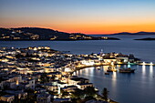 Blick über die Stadt mit den berühmten Windmühlen von Mykonos und dem Hafen, gesehen von der 180º Sunset Bar in der Abenddämmerung, Mykonos, Südliche Ägäis, Griechenland, Europa