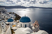 Blue dome of a Greek orthodox church with bell tower and houses on cliffs, Oia, Santorini, South Aegean, Greece, Europe