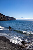 Zwei junge Frauen an felsigem Strand und Küste, in der Nähe von San Sebastián de La Gomera, La Gomera, Kanarische Inseln, Spanien, Europa