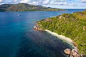 Aerial view of beach in small bay with granite boulders and boutique cruise ship M/Y Pegasos (Variety Cruises) in distance, Curieuse Island, Seychelles, Indian Ocean