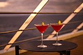 Zwei Cocktailgläser auf einem Tisch an Bord von Expeditionskreuzfahrtschiff World Voyager (nicko cruises) bei Sonnenuntergang, in der Nähe von Puerto Jiménez, Puntarenas, Costa Rica, Mittelamerika