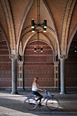 Woman on bicycle rides through portal of the Rijksmuseum (Rijksmuseum), Amsterdam, province of North Holland, The Netherlands, Europe