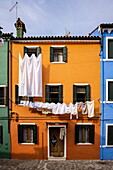 Laundry hangs to dry outside a brightly colored house, Burano, Venice, Italy, Europe