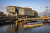 Ausflugsboot auf Kanal und modernes Gebäude, Amsterdam, Nordholland, Niederlande, Europa