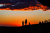 Schatten und Shilouetten von Personen bei der Beobachtung vom Sonnenuntergang am Inselberg Spitzkuppe in Namibia, Afrika