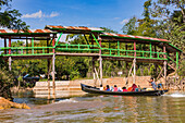 Ein traditionelles Langboot auf einem Kanal im Inle-See zum Personentransport unter einer Fußgängerbrücke aus Holz, Myanmar, Asien