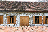 Winery building with white stone walls covered with grape and shingles roof in sunny day