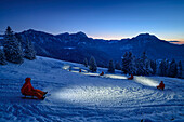Person drives in headlamp light with sled from Farrenpoint, Farrenpoint, Bavarian Alps, Upper Bavaria, Bavaria, Germany