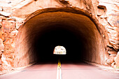 A road leading into a tunnel in the landscape of the Zion National Park in Utah, USA.
