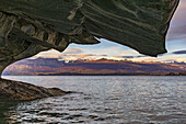 Ausblick auf die Berge der Anden durch eine Marmorformation der Cuevas de Marmol im Lago General Carrera, Chile, Patagonien, Südamerika