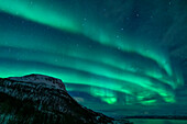 Aurora Borealis over the fjord landscape of the Lyngen Alps, Norway.