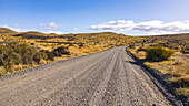 Eine Schotterstraße durch die Steppenlandschaft im südlichen Patagonien, Chile, Südamerika