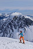 Frau auf Skitour steigt zum Kleinen Frauenkogel auf, Hahnkogel und Hochstuhl im Hintergrund, Rosental, Karawanken, Kärnten, Österreich