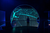 Woman looks at visualizations in a pavilion in Autostadt in Wolfsburg, Lower Saxony, Germany, Europe