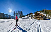 Woman cross-country skiing running towards an alpine hut, Bayrischzell, Mangfall Mountains, Bavarian Alps, Upper Bavaria, Bavaria, Germany