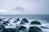 Surf with large rocky roundels and mountain in clouds, Ballesvika, Senja, Troms og Finnmark, Norway