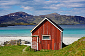 Norwegen, Nordland, Lofoten, Flakstadøy, rote Hütte am Strand von Ramberg
