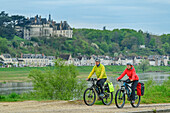 Mann und Frau beim Radfahren mit Château de Chaumont im Hintergrund, Loire-Radweg, Loire-Schlösser, Loiretal, UNESCO Welterbe Loiretal, Frankreich