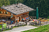 Mehrere Personen sitzen an der Einkehr Litzlalm, Litzlalm, Berchtesgadener Alpen, Salzburg, Österreich
