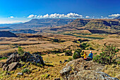Mann und Frau beim Wandern sitzen auf Felsen und blicken auf Little Berg, Baboon Rock, Didima, Cathedral Peak, Drakensberge, Kwa Zulu Natal, UNESCO Welterbe Maloti-Drakensberg, Südafrika
