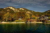 Blick vom Wolfgangsee auf Alpenhäuser und Bootshäuser am Seeufer, im Hintergrund die Berge des Salzkammerguts, Österreich