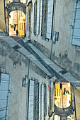 Grafische Doppelbelichtung einer Person, die durch ein gewölbtes Tor in der mittelalterlichen Stadt Arles, Frankreich, geht.