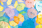 Multiple exposure of colorful umbrellas suspended over a street to provide shade in Bordeaux, France.