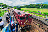 Menschen am Bahnhof an der Bahnstrecke des Marumaru no Hanashi Zuges, San'in-Linie entlang der westlichsten Küste von der Hauptinsel Honshū, Japan
