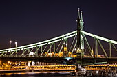 Illuminated Liberty Bridge over the Danube with Buda Castle in the distance at night, Budapest, Pest, Hungary, Europe