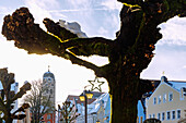 Houses on the street Lange Zeile and the city tower of the parish church of St. Johann with snow and Christmas decorations in Erding in Upper Bavaria in Germany