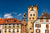 Löwe mit Stadtwappen am Marktbrunnen vor dem Rathaus und der Metzgerturm in Ribeauville, Elsass, Frankreich 