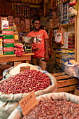  Happy man at a fruit and vegetable stall in the market hall, Chaka Chaka, Pemba Island, Tanzania, Africa 