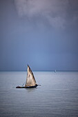  Traditional dhow sailboat with storm clouds in the background, Stonetown, Zanzibar City, Zanzibar, Tanzania, Africa 
