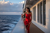  Woman with cocktail glass on the railing of the expedition cruise ship SH Diana (Swan Hellenic), at sea, near the Seychelles, Indian Ocean 