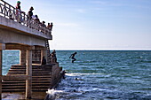 Pier am Strand mit Menschen, die ins Meer springen, Mahajanga, Boeny, Madagaskar, Indischer Ozean