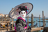  Asian mask on the Grand Canal during Venice Carnival, Venice, Italy 