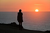 Frau blickt auf den Sonnenuntergang am Strand Praia Sao Juliao bei Ericeira, Atlantikküste, Region Lissabon, Portugal