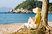 Frau liest ein Buch am Strand, Bombinhas, Santa Catarina, Brasilien