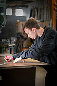 Jugendlicher bei der Arbeit in einer Werkstatt, Schweiz