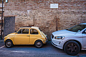  small Fiat 500 stands next to large SUV car, Siena, Tuscany region, Italy, Europe 
