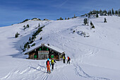 Vier Personen auf Skitour stehen an Almhütte, am Tanzeck, Spitzinggebiet, Bayerische Alpen, Oberbayern, Bayern, Deutschland