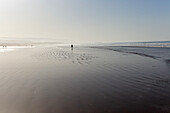 Silouette of people walking on beach at low tide, Taghazout, Morocco, North Africa