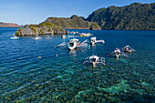  Aerial view of Bangka outrigger canoe tour boats and snorkelers in Siete Pecados, a cluster of seven small islands, Coron, Palawan, Philippines 