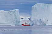 Touristenboot vor Eisbergen, Kangia Eisfjord, Disko-Bucht, UNESCO-Weltnaturerbe, West-Groenland, Grönland